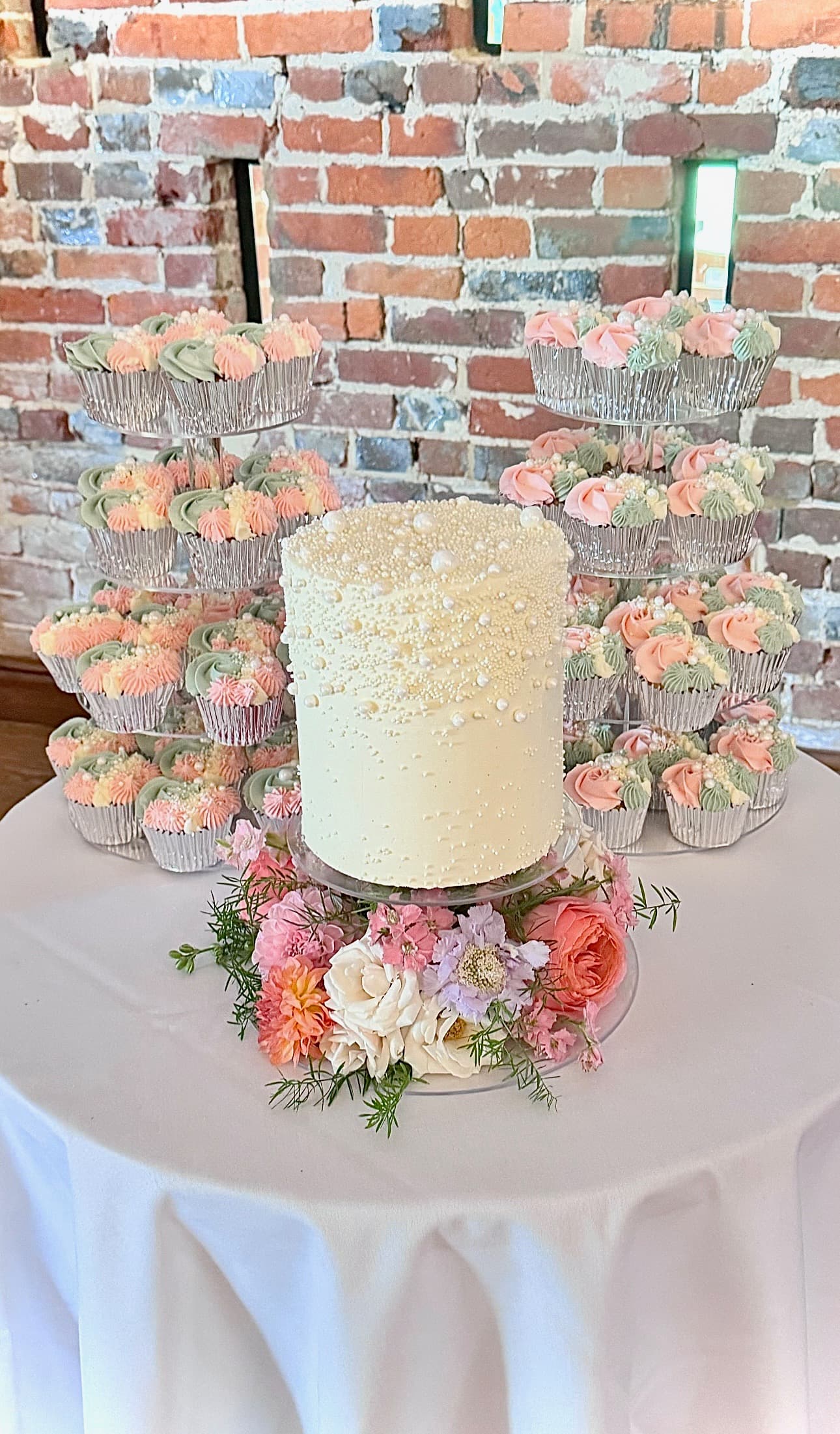 Close-up white wedding cake with flowers and a ring of leaves surrounding