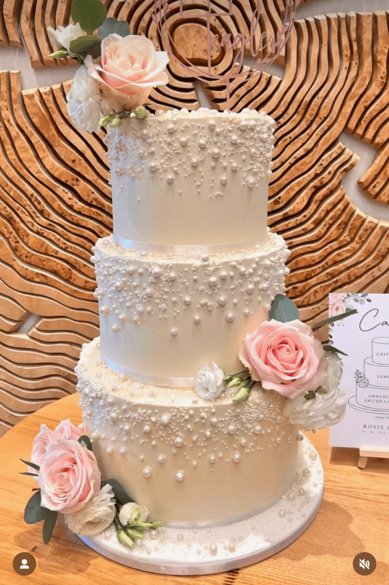 White and rose coloured two-tiered wedding cake with flowers on top