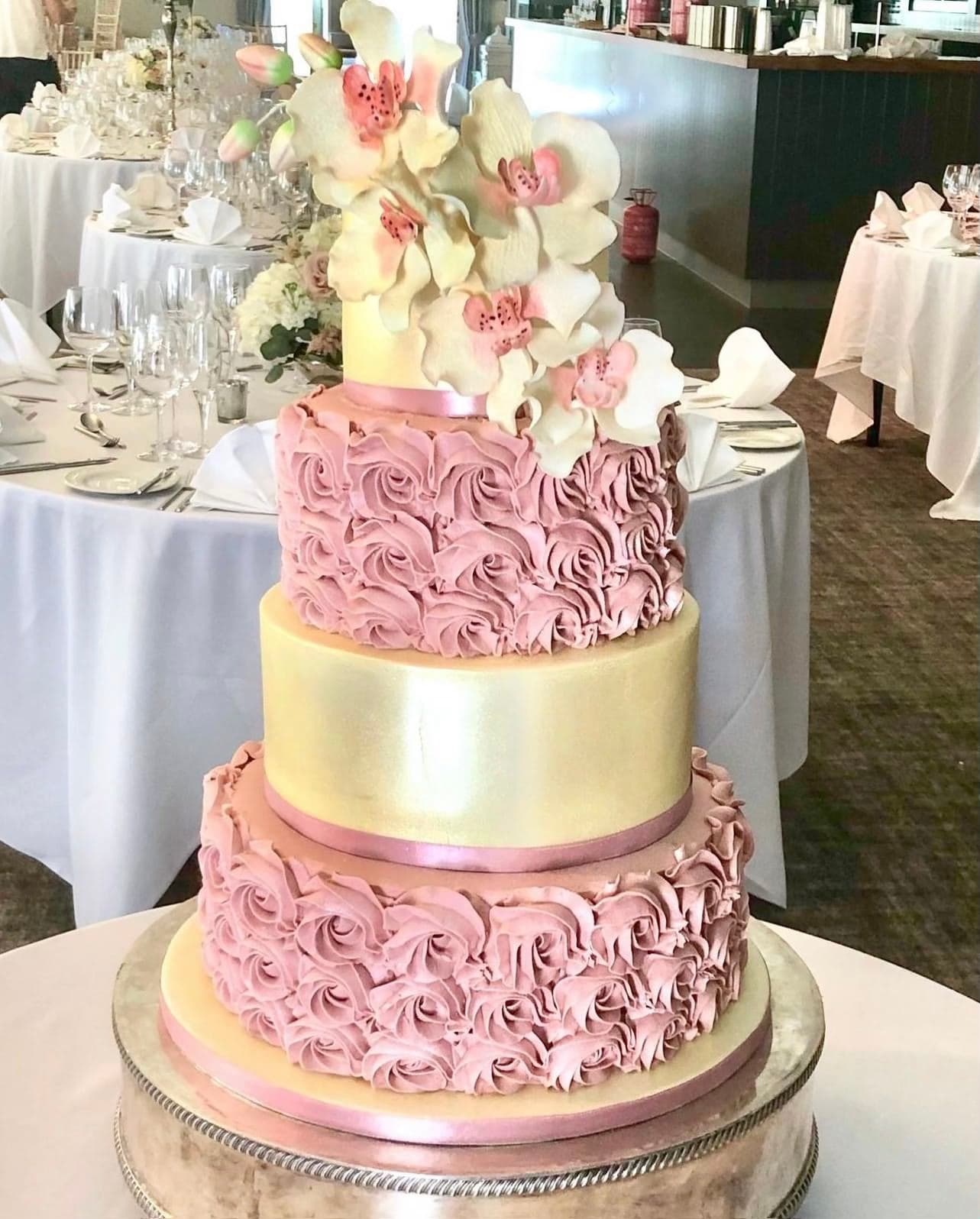 White and cream wedding cake with swirly icing flowers and flowers on the top